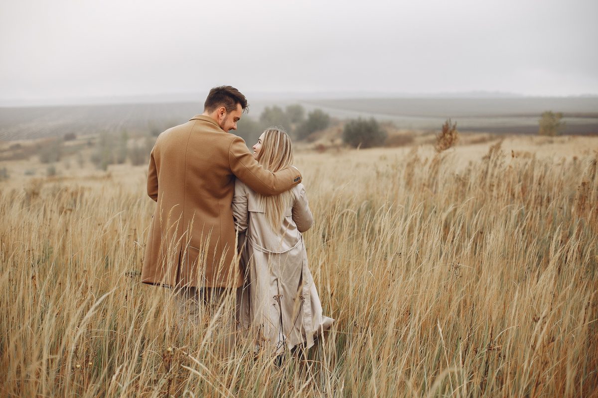 Couple walking together through a field in coats
