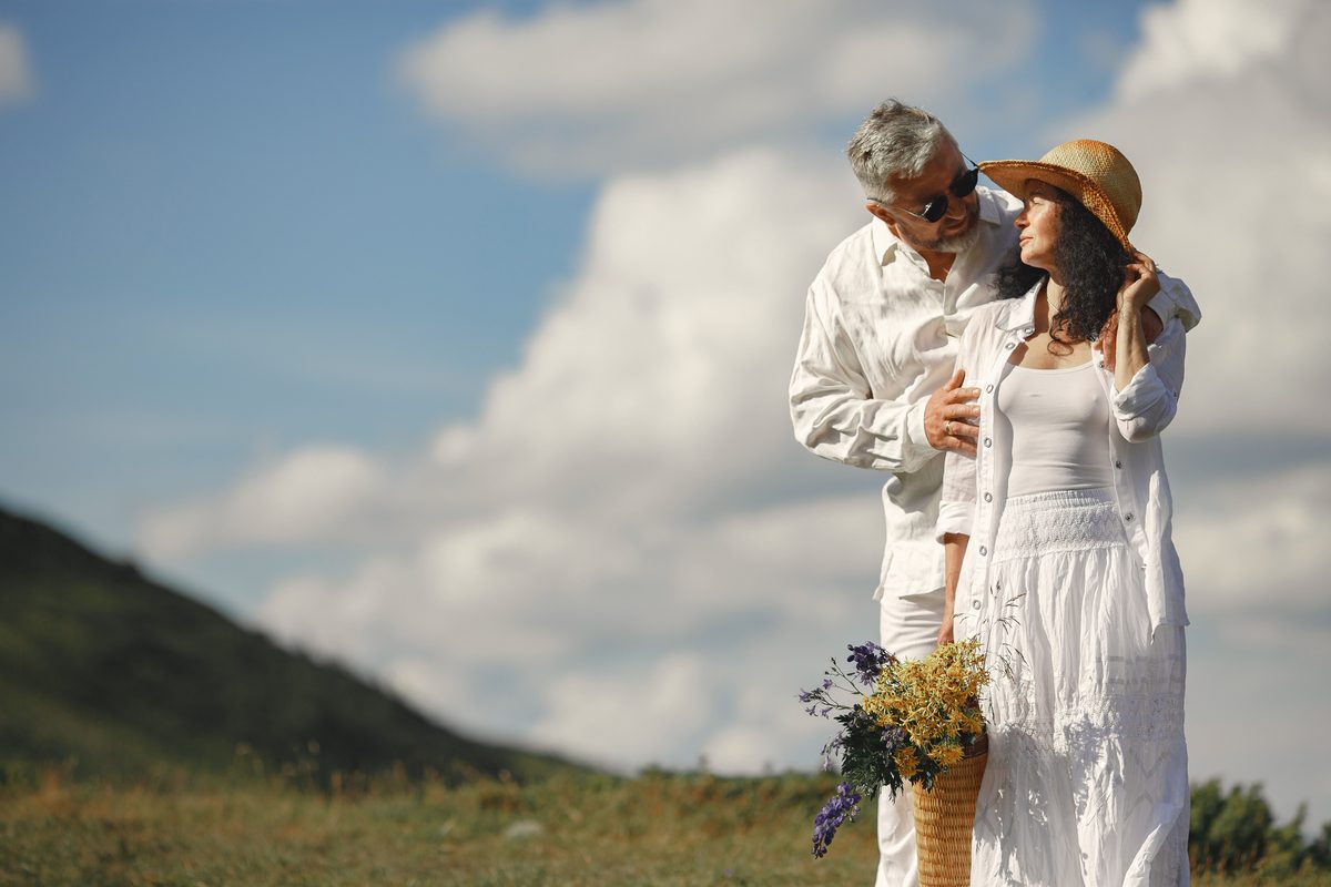 Couple standing on a grassy hillside with wildflowers
